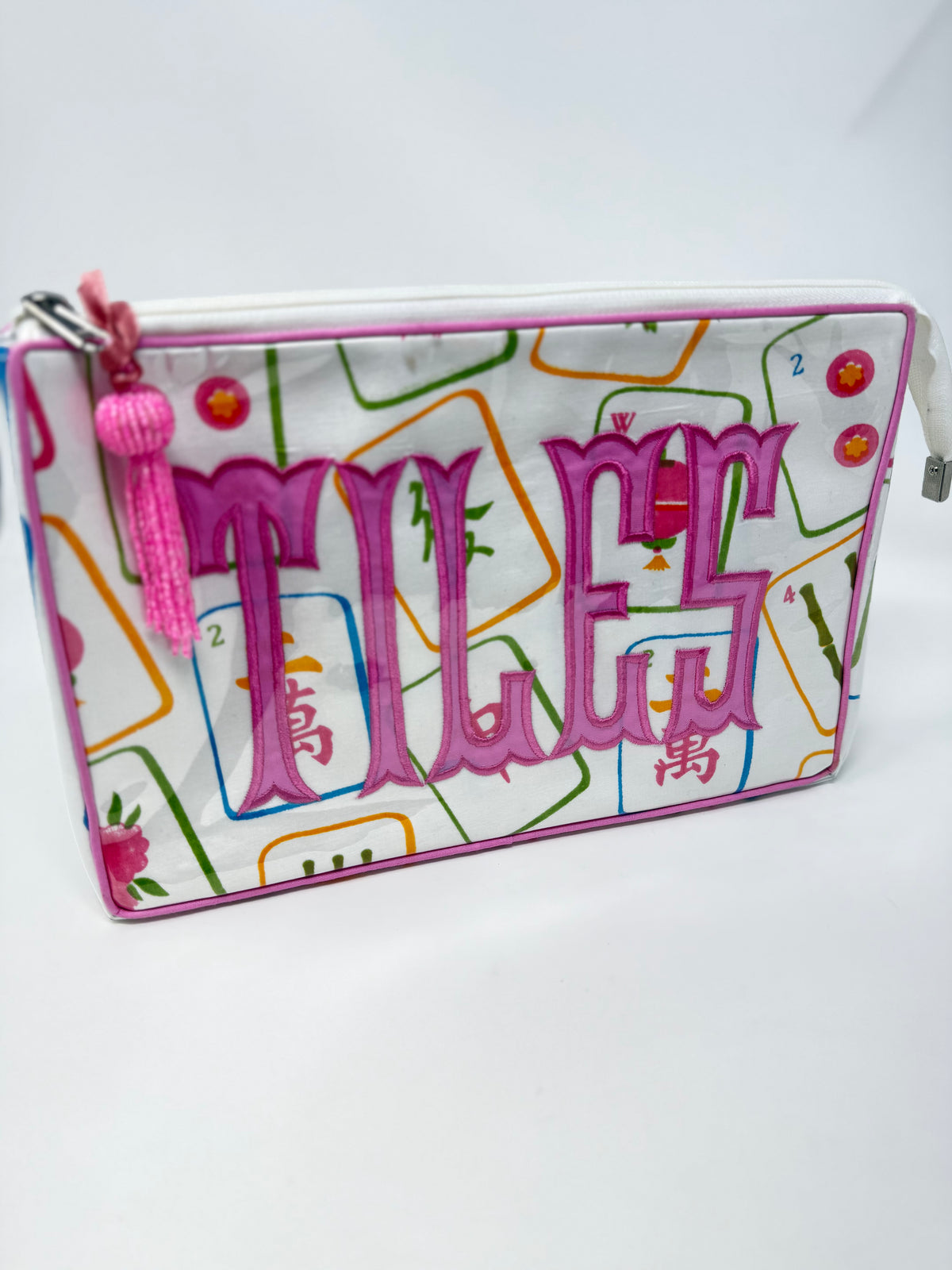 Tiana cosmetic bag with mahjong tile pattern and pink embroidered 'TILES' text and tassel.