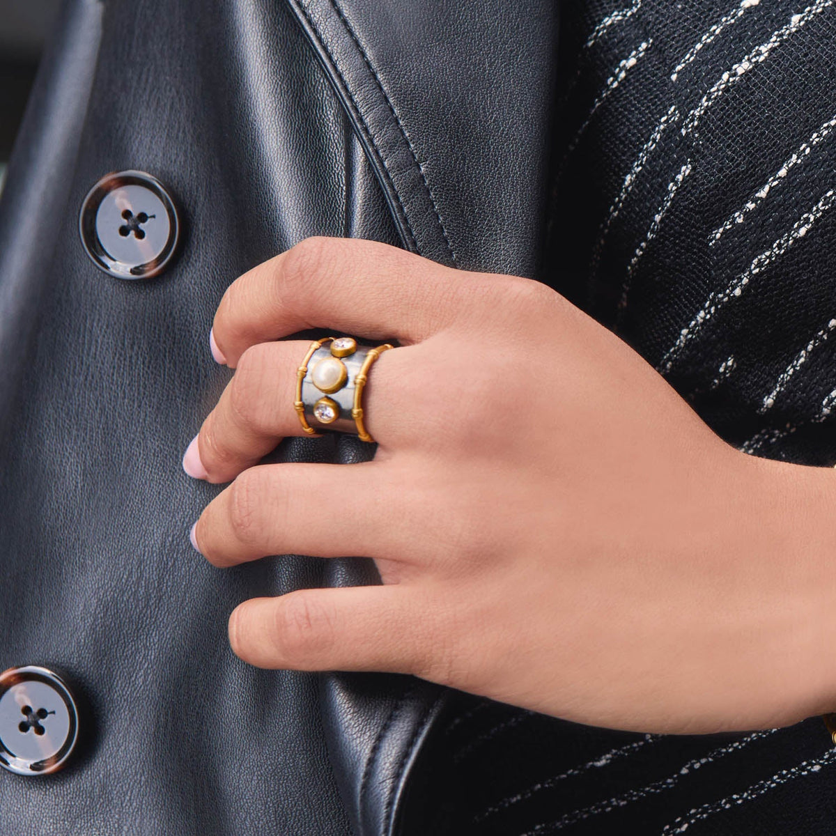 Tribeca Ring in 24K gold plate with shell pearl and CZ on a person's hand.