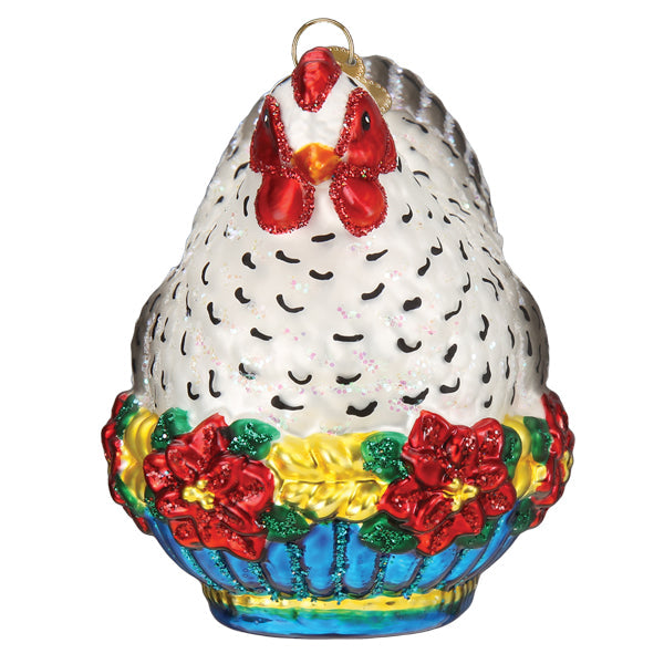 Glass French hen ornament with white feathers, red comb, and a base of poinsettias and blue basket.