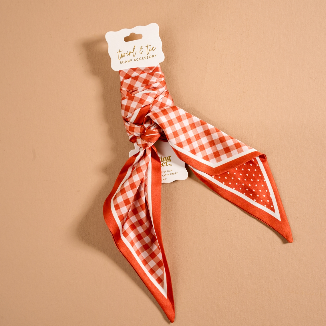 Twirl & Tie Scarf Accessory in red and white gingham and polka dot patterns on a display card.
