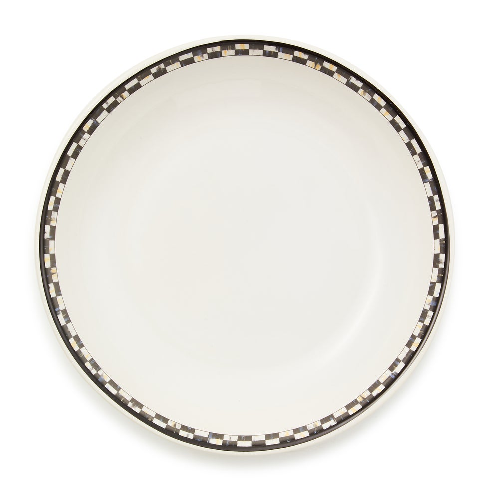 Top view of a white stoneware pasta bowl with a black and white checkered pattern around the rim.