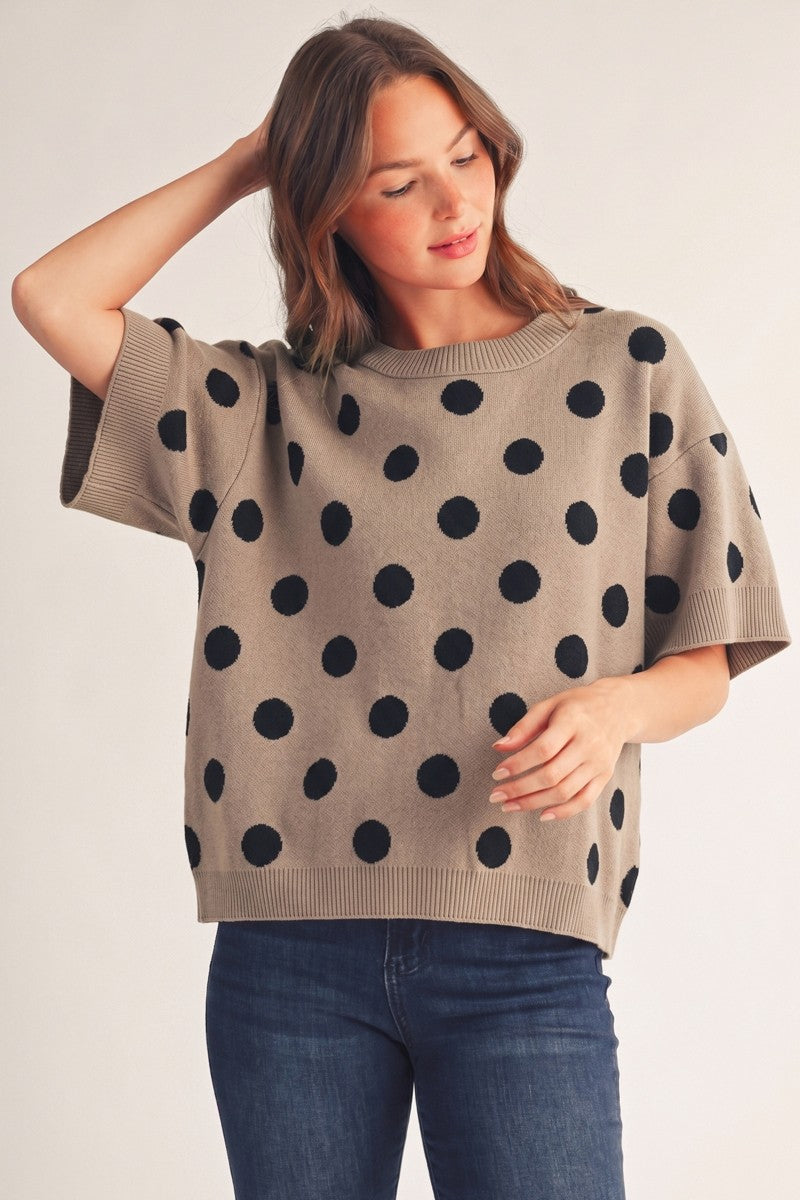 Woman wearing the Emily Polka Dot Comfy Sweater Top in taupe with large black dots and blue jeans.