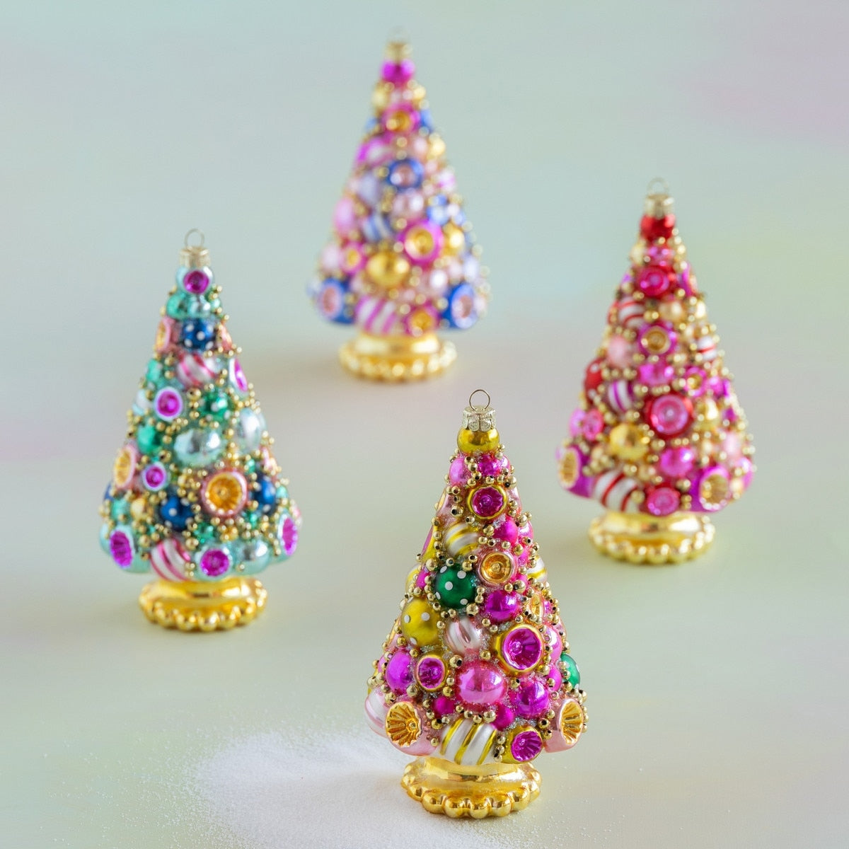 Four vibrantly lacquered glass tree ornaments with colorful beads and golden bases.