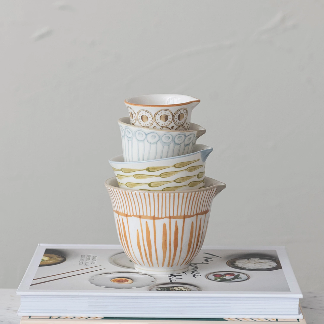 Set of four stoneware measuring cups with colorful geometric patterns.