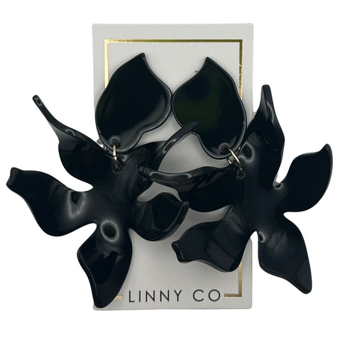 Pair of oversized black Flora earrings with a glossy finish on a white display card.