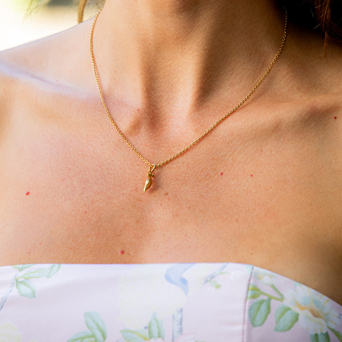A person wearing the Meadow Walk Lily Charm Necklace in 18K gold plated brass.