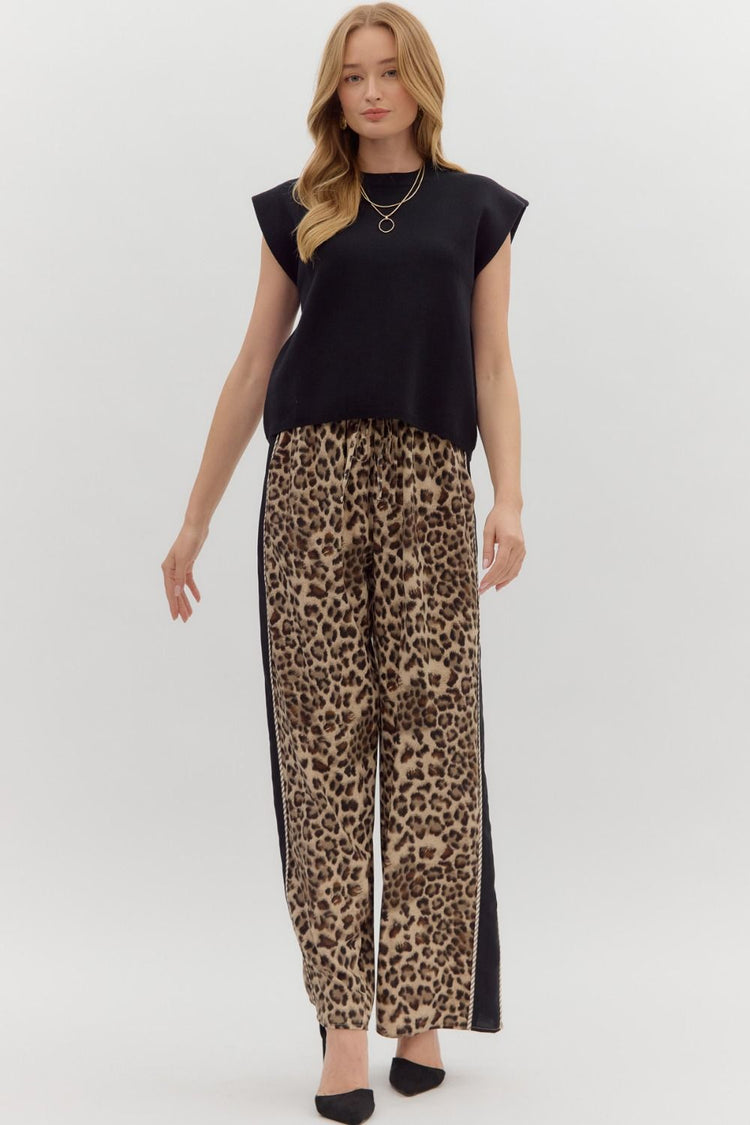 Woman wearing a black Olivia solid crewneck sweater knit muscle tee top with leopard print pants.