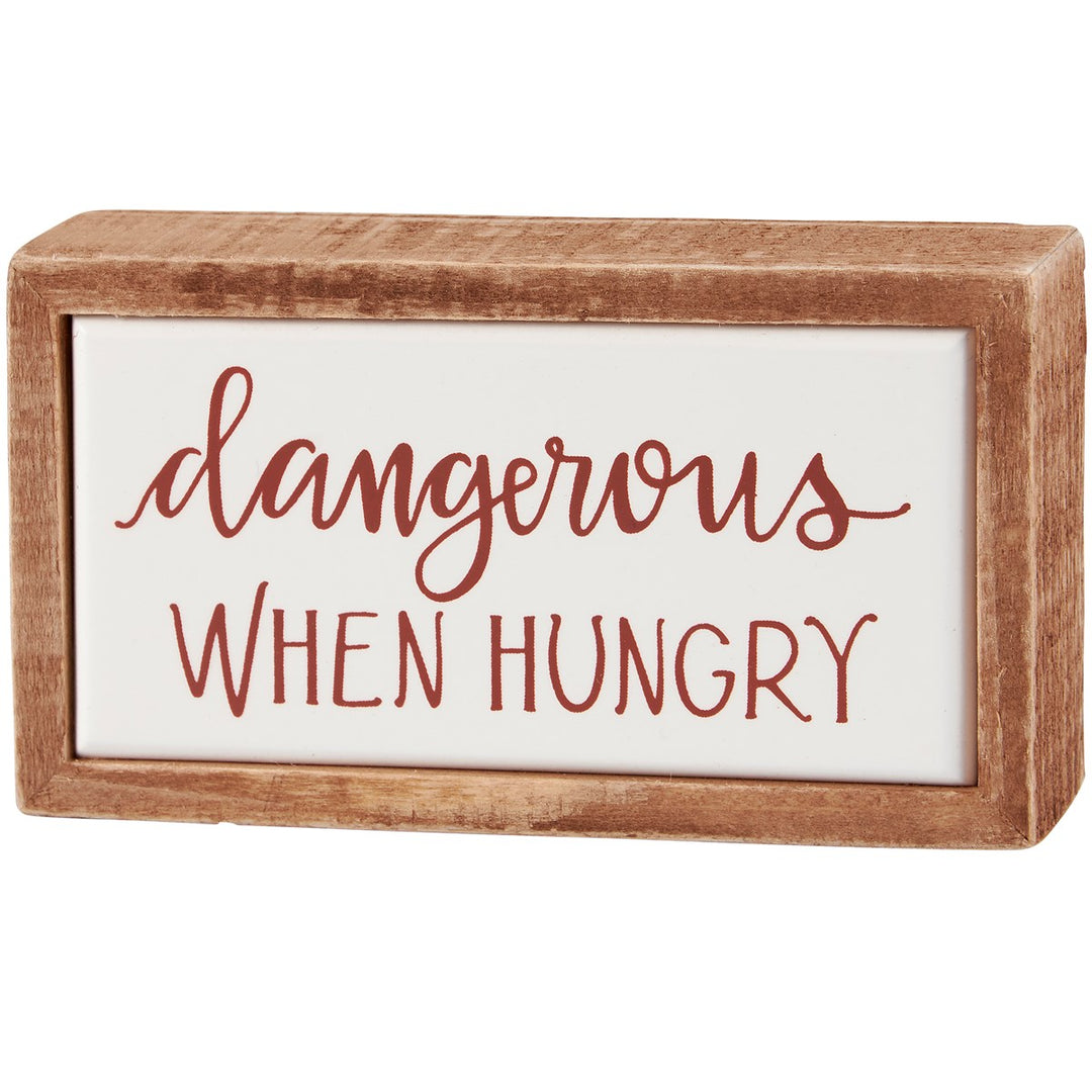 Small wooden box sign with 'dangerous WHEN HUNGRY' text in brown script and block lettering.