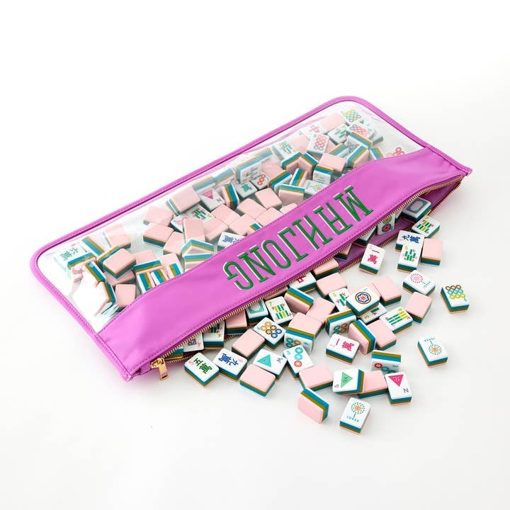 La Fete Mahjong tiles in pink, green, and teal spilling out of a pink zippered pouch.