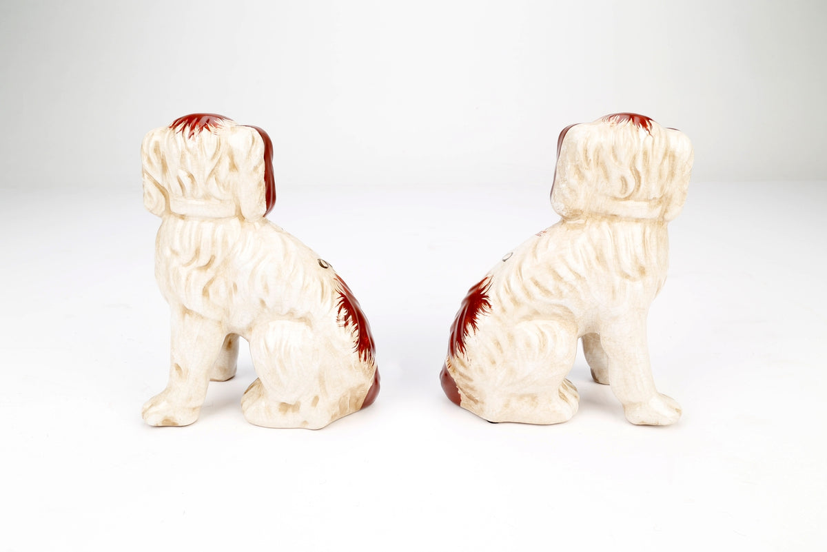 Rear view of a pair of brown and white Staffordshire-style ceramic dogs with gold collars.