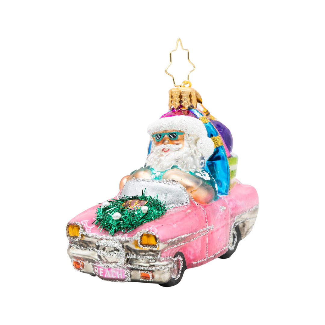 Santa in a pink convertible glass ornament with a surfboard, sunglasses, and a beach wreath.
