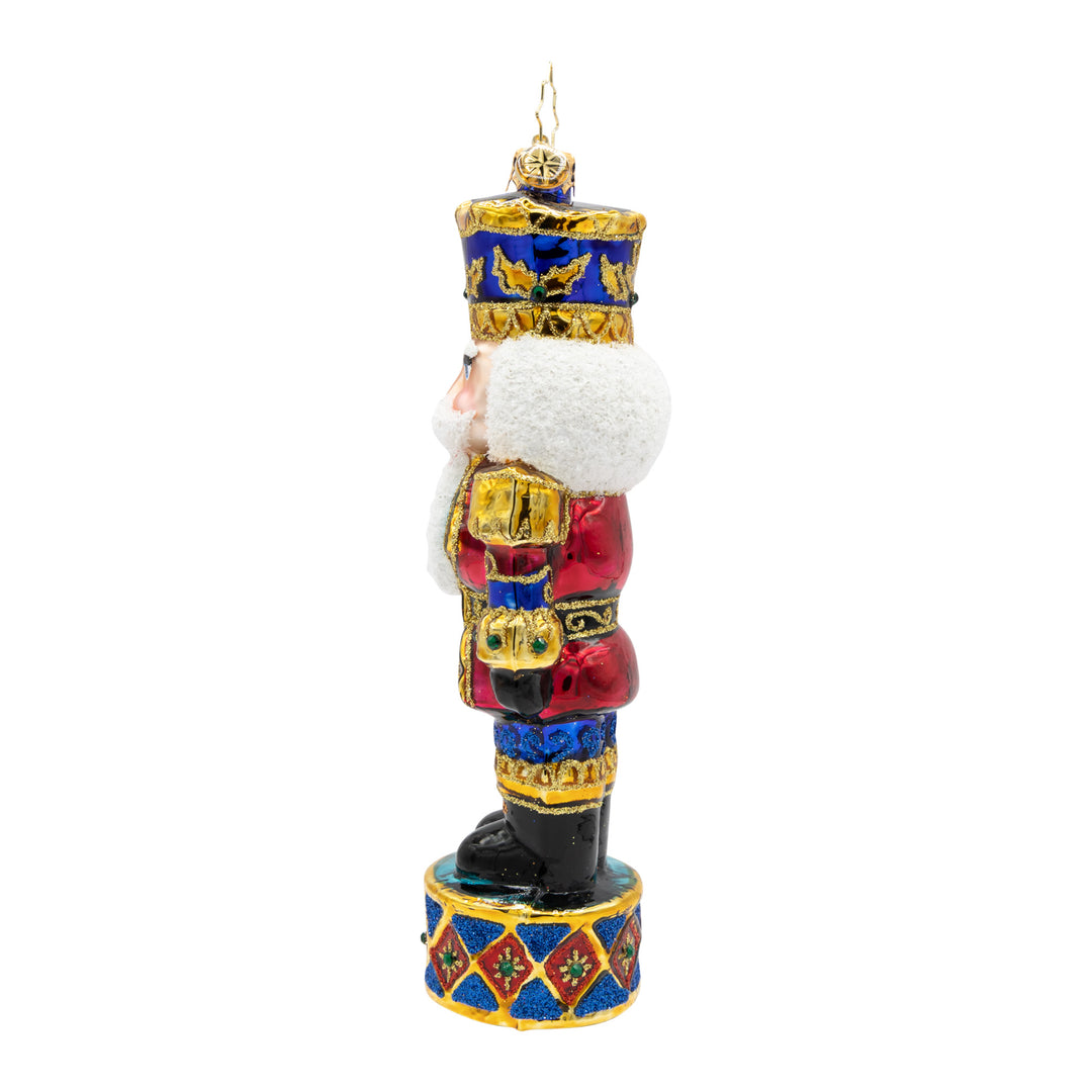 Side view of a Radiant Jewel Nutcracker ornament in ruby, sapphire, and gold with a white beard.