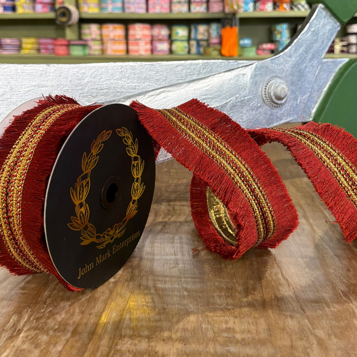 Burgundy metallic dupion ribbon with double-sided fringe trim on a John Mark Enterprises spool.