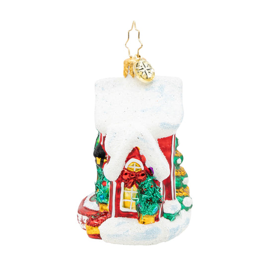 Glass Christmas ornament of a red house with a snow-covered roof and festive decorations.