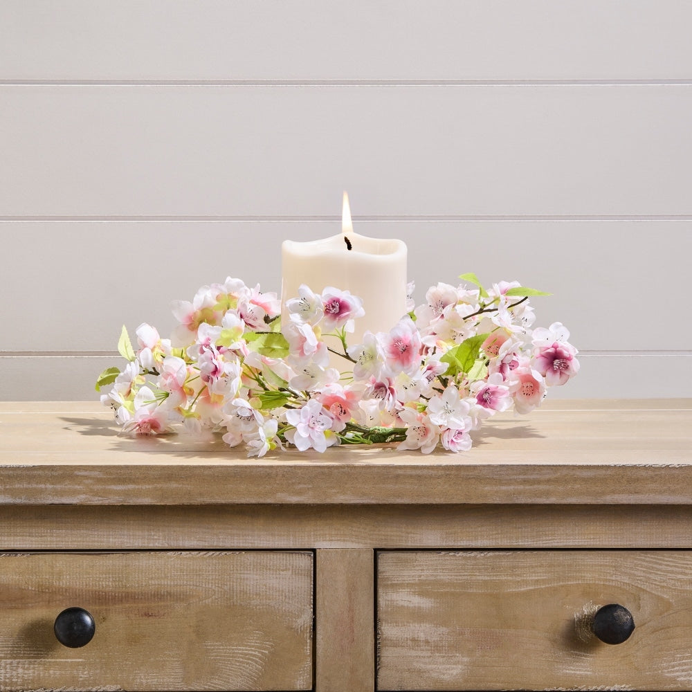 A round cherry blossom wreath made of polyester with lifelike pink blooms on a white background.