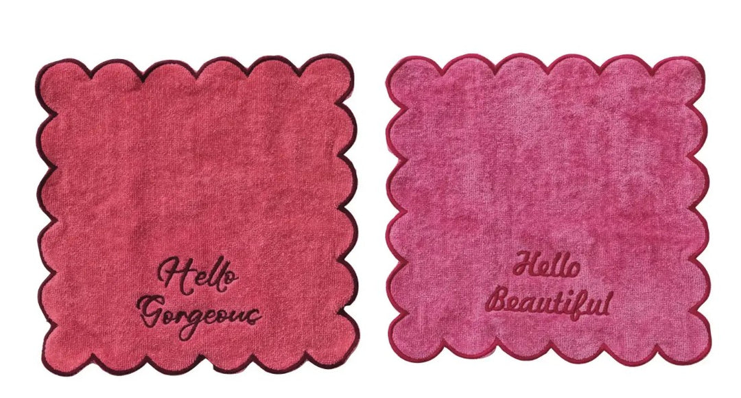 Two pink square cotton cloths with scalloped edges embroidered with Hello Gorgeous and Beautiful.