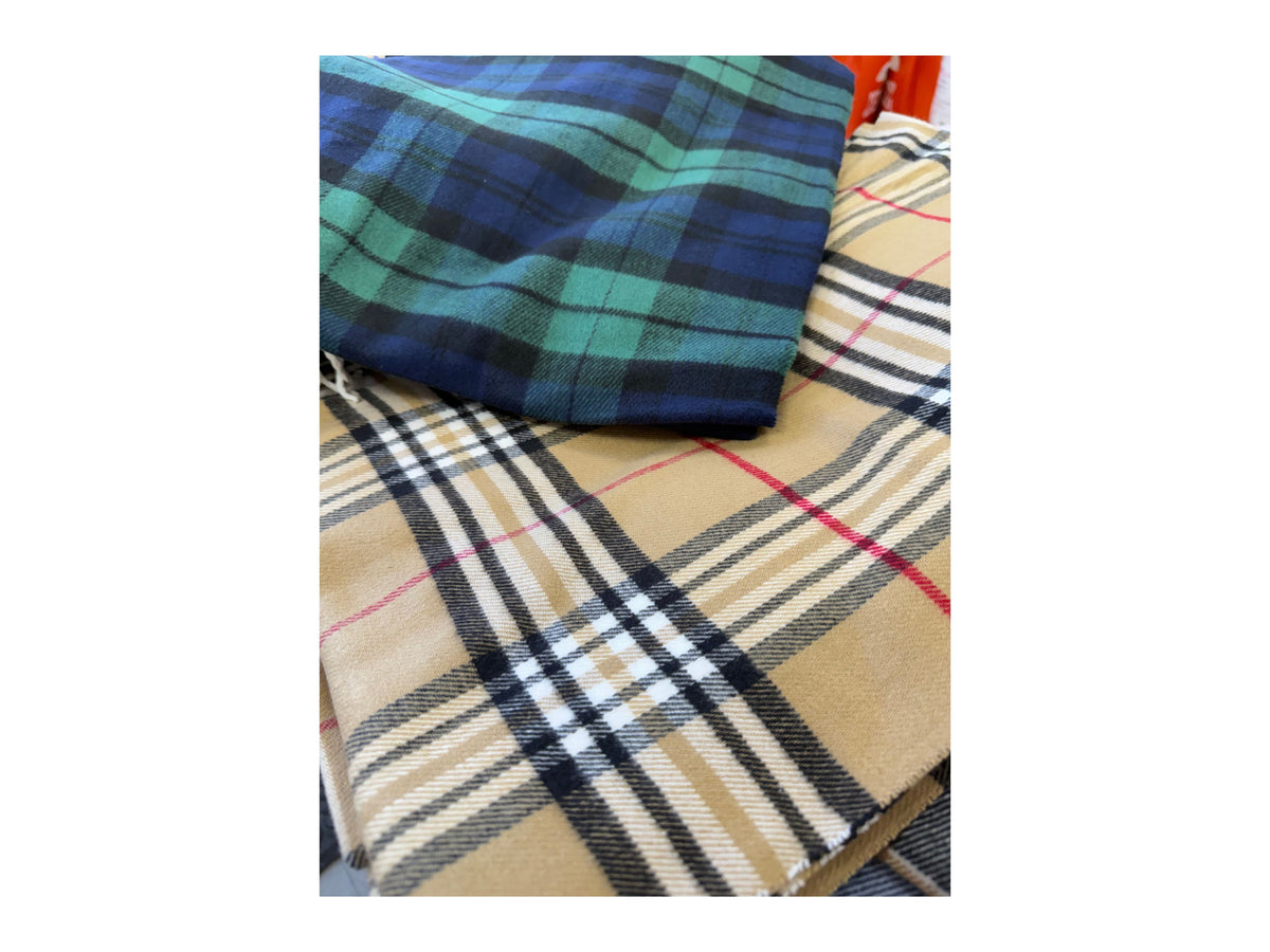 Two folded Scottish plaid cashmere scarves in green/blue and tan/black/red patterns.