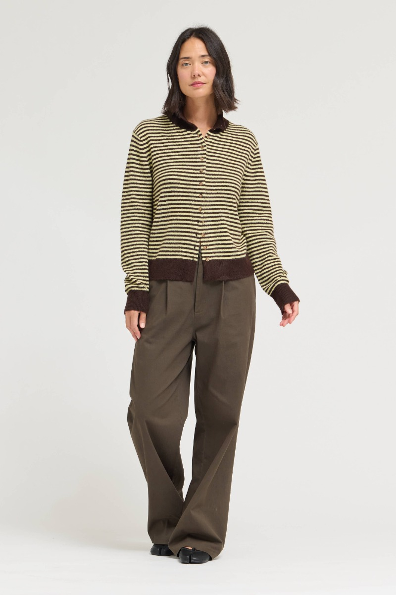 Woman wearing a Megan Mock Neck Striped Sweater Cardigan in yellow and brown with brown trousers.