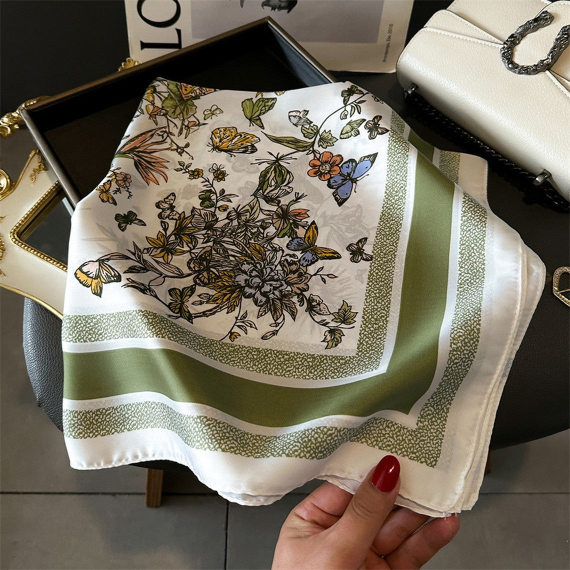 Silky white square scarf with a green border and colorful butterfly and floral print.