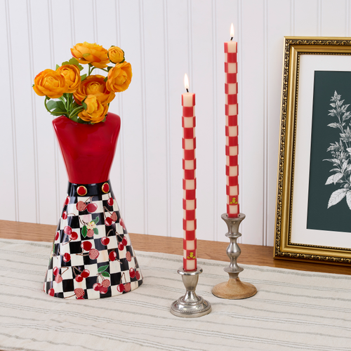 Mon Cheri Tall Dress Vase with orange flowers, checkered candles, and a framed picture on a table.