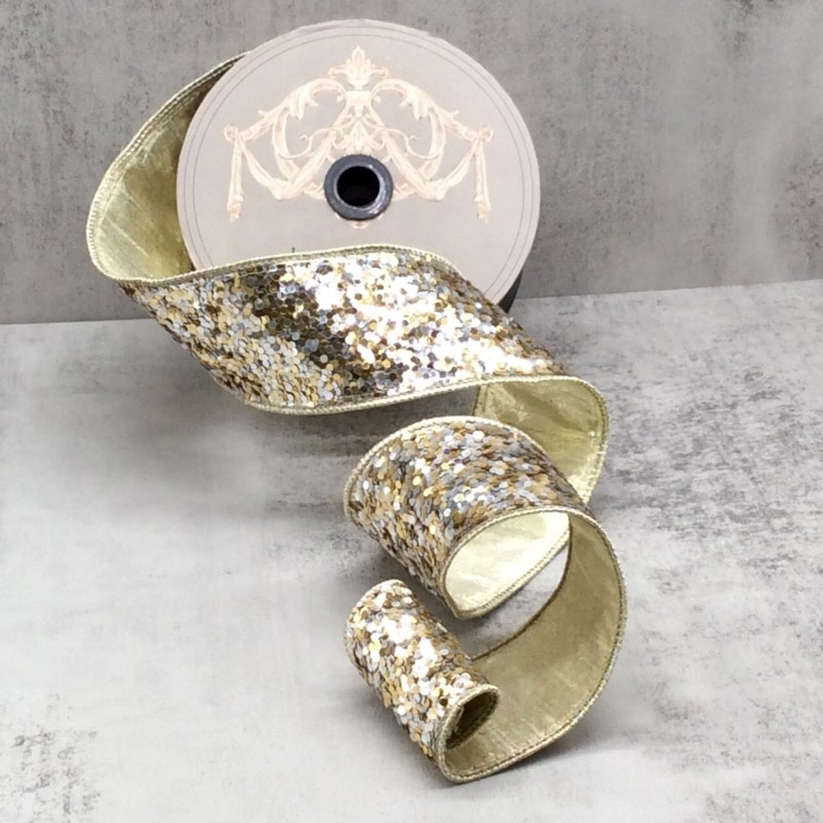 2.5 inch wide silver and gold cirque glitter ribbon on a spool, cascading in curls.