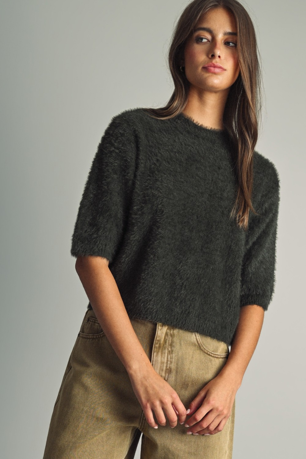 Model wearing Alexa Fluffy Cropped Faux-fur Sweater in dark brown with round neck and short sleeves.