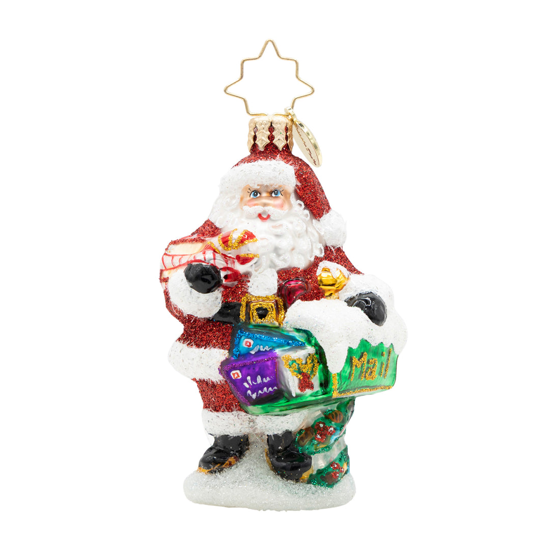 Glass Santa ornament holding a mailbox and letters, decorated with red glitter and white snow.