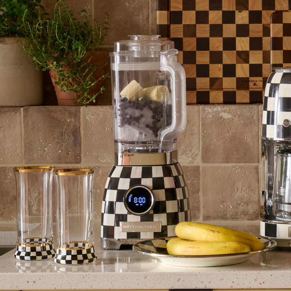 Courtly Check Blender with a black and white checkered base, filled with fruit on a kitchen counter.