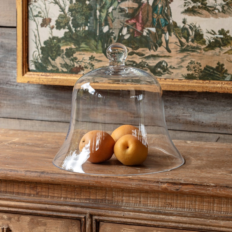 Medium glass bell jar garden cloche covering three pears on a rustic wooden surface.