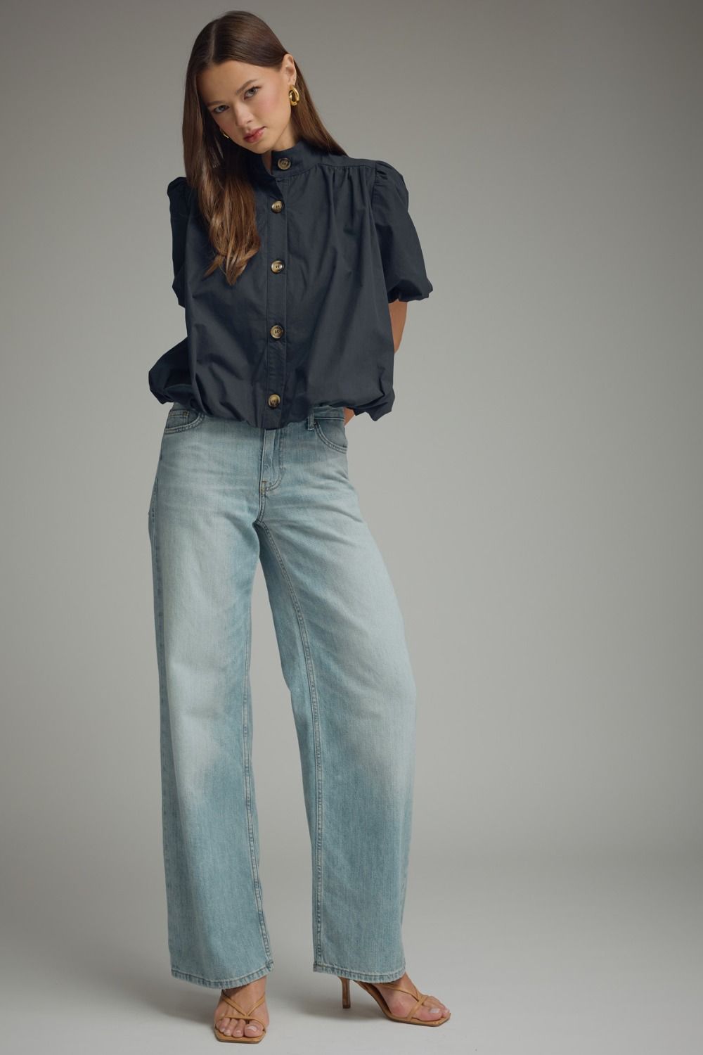 Woman wearing a navy Jacky Short Puff Sleeve Top with a bubble hem and light wash wide-leg jeans.