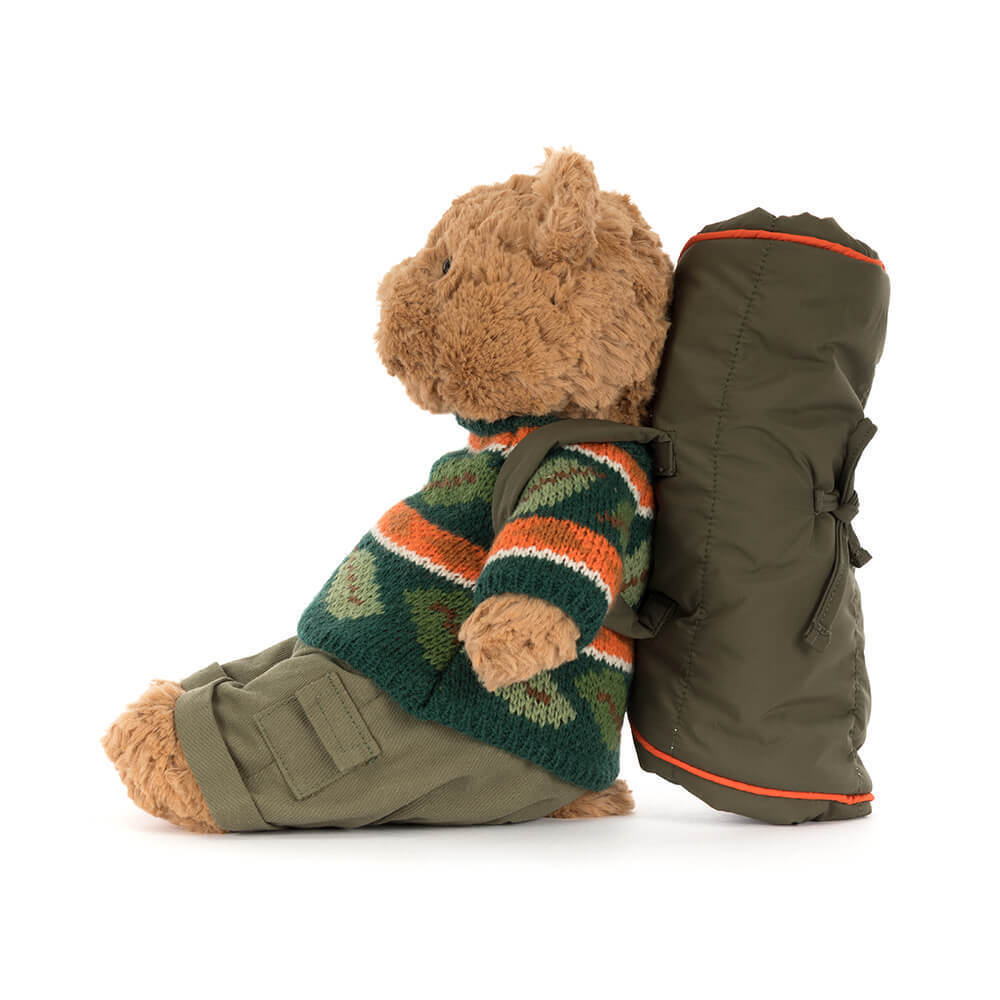 Side view of Bartholomew Bear in a green knit sweater and cargo pants with a rolled sleeping bag.