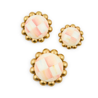 Three round Mackenzie-Childs magnets in small, medium, and large with pink checkered patterns.