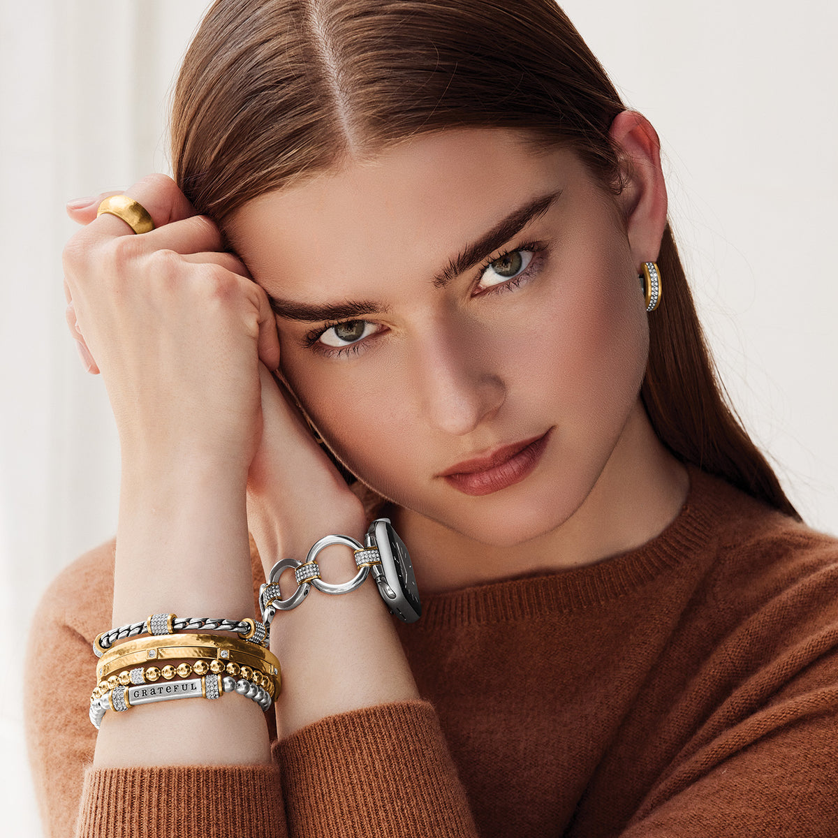 A woman wearing a stack of two-tone Meridian bracelets with silver and gold finishes.
