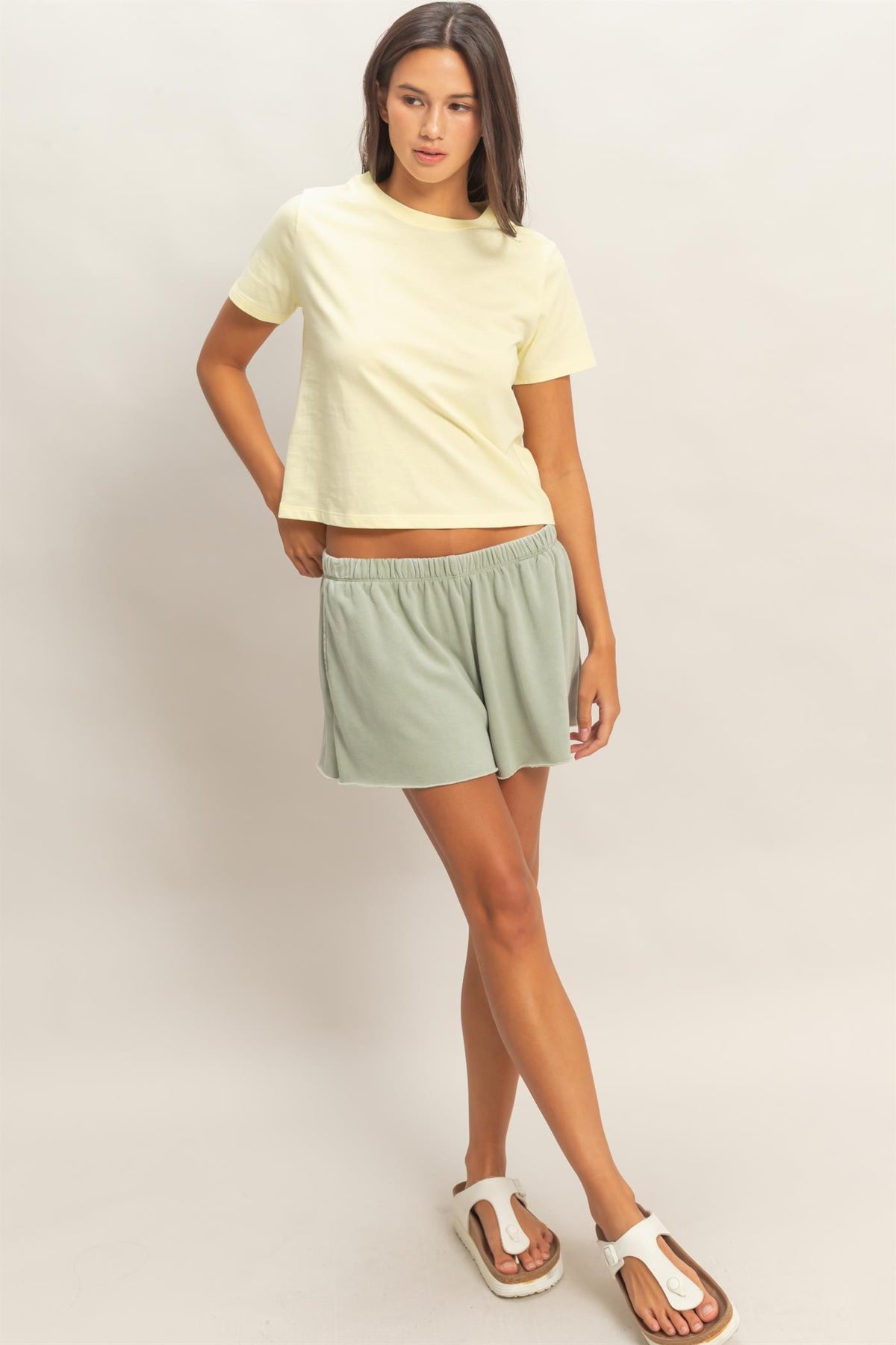 Woman wearing a Zyrah pale yellow crew neck cotton t-shirt and light green shorts.