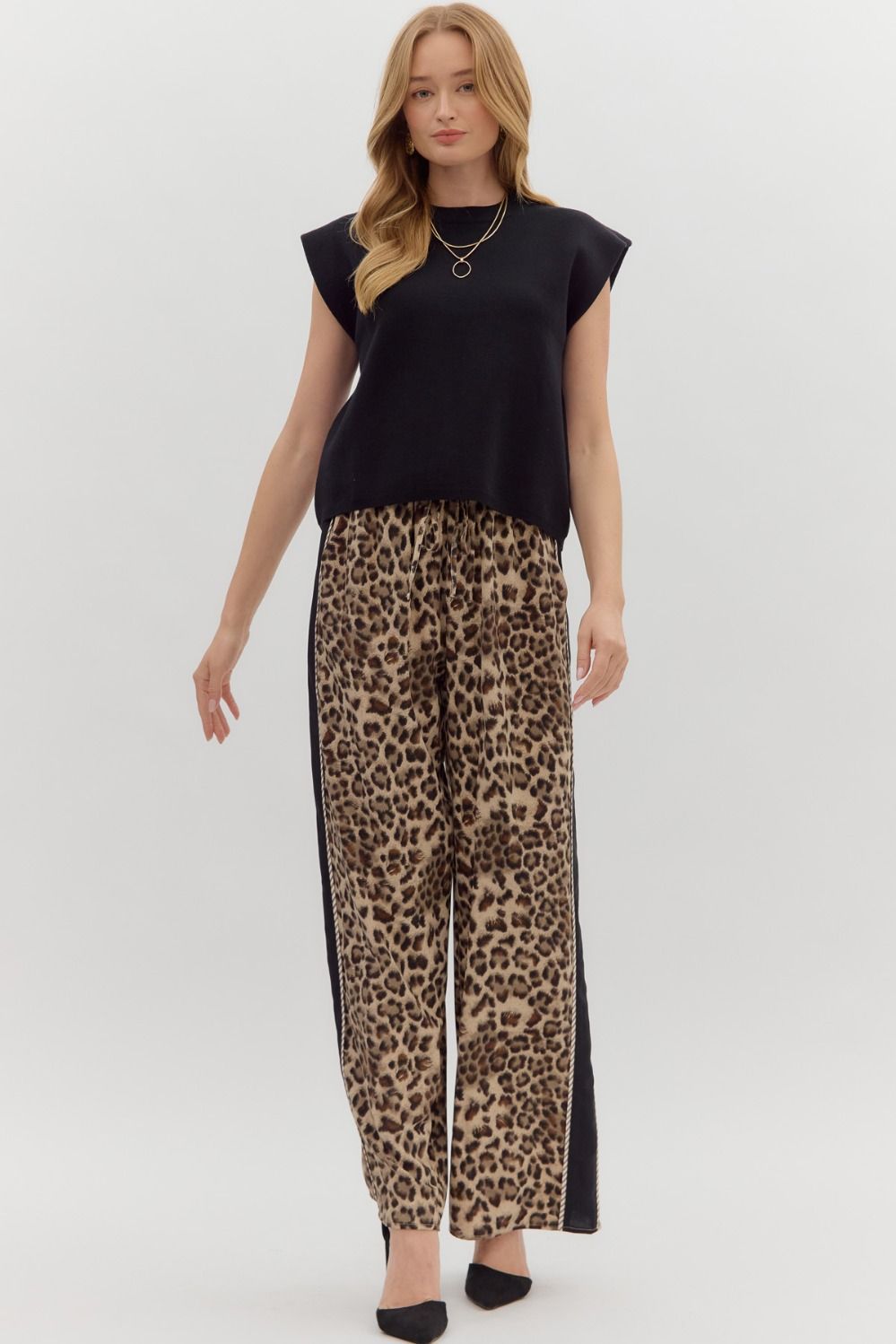 Woman wearing a black Olivia solid crewneck sweater knit muscle tee top with leopard print pants.