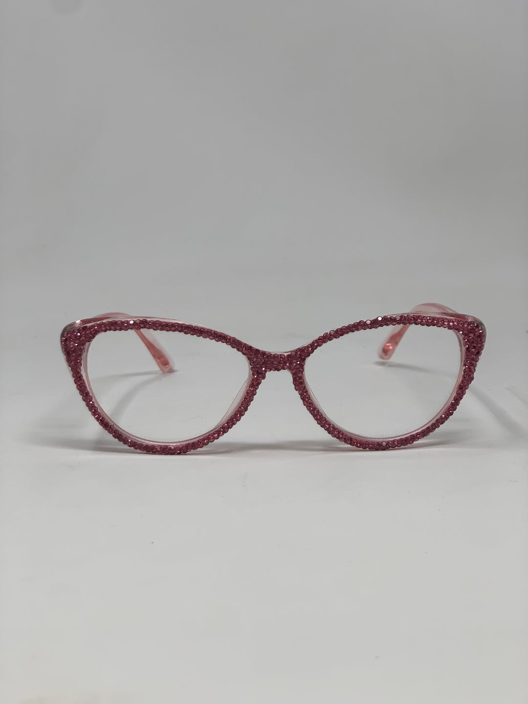 Pink cat-eye reading glasses with frames fully covered in shimmering pink rhinestones.