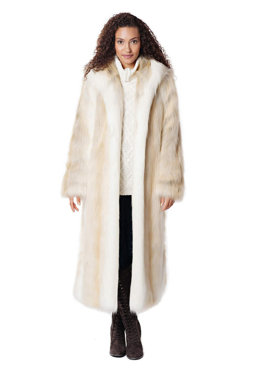 Woman wearing a long, hooded faux fur coat in white and tan over a white sweater and dark boots.