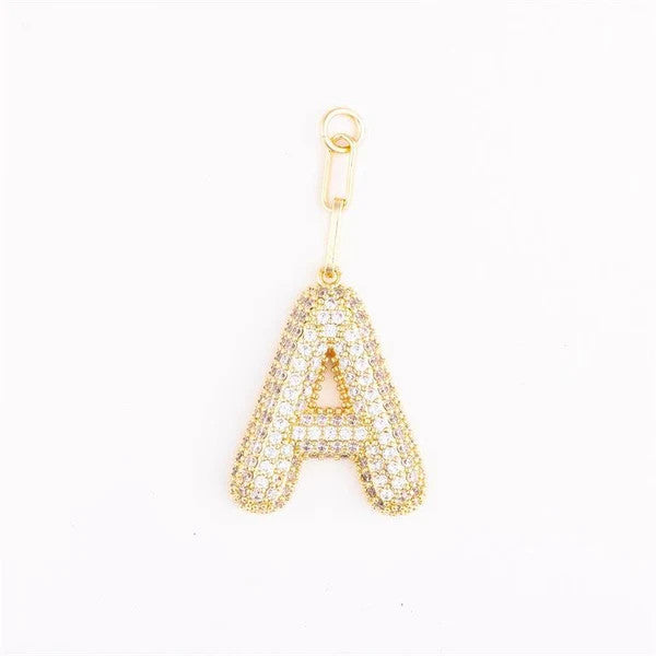 Heather-colored charm bag with gold plating, pave crystal accents, one-inch size, and customizable initial.