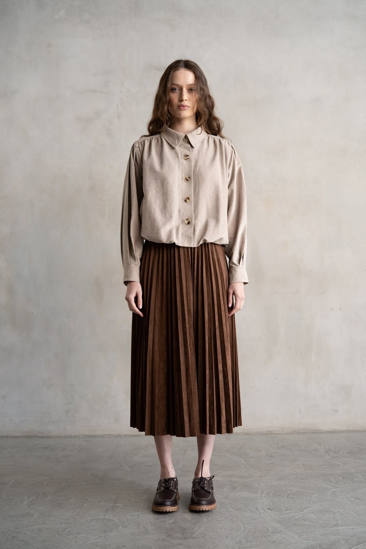 Maddie elastic waist pleated midi skirt in light beige with a soft sheen and structured silhouette.
