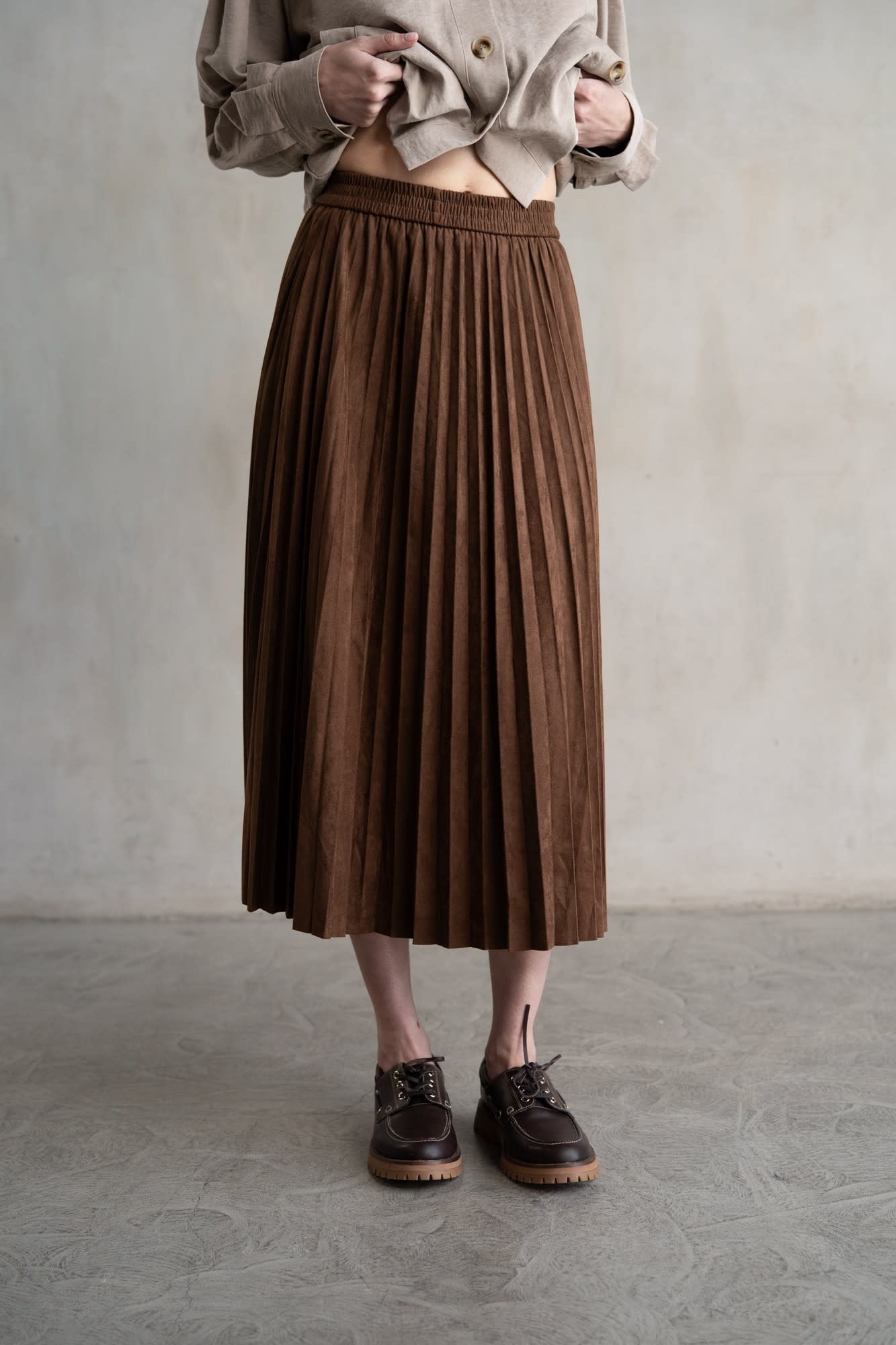 Maddie elastic waist pleated midi skirt in black with a soft sheen and structured silhouette.