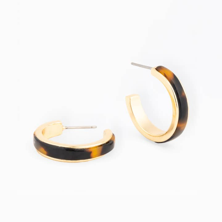 A pair of Josie gold-rimmed hoop earrings with a dark brown tortoiseshell resin inlay.