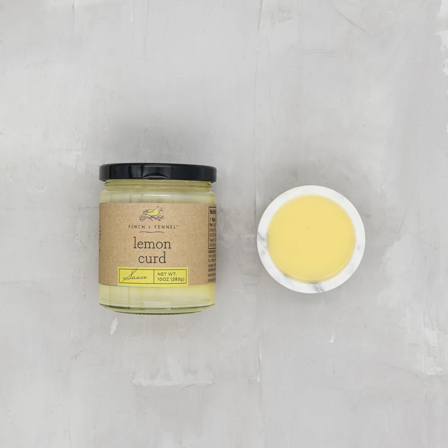 A jar of bright yellow lemon curd sauce with a white lid.