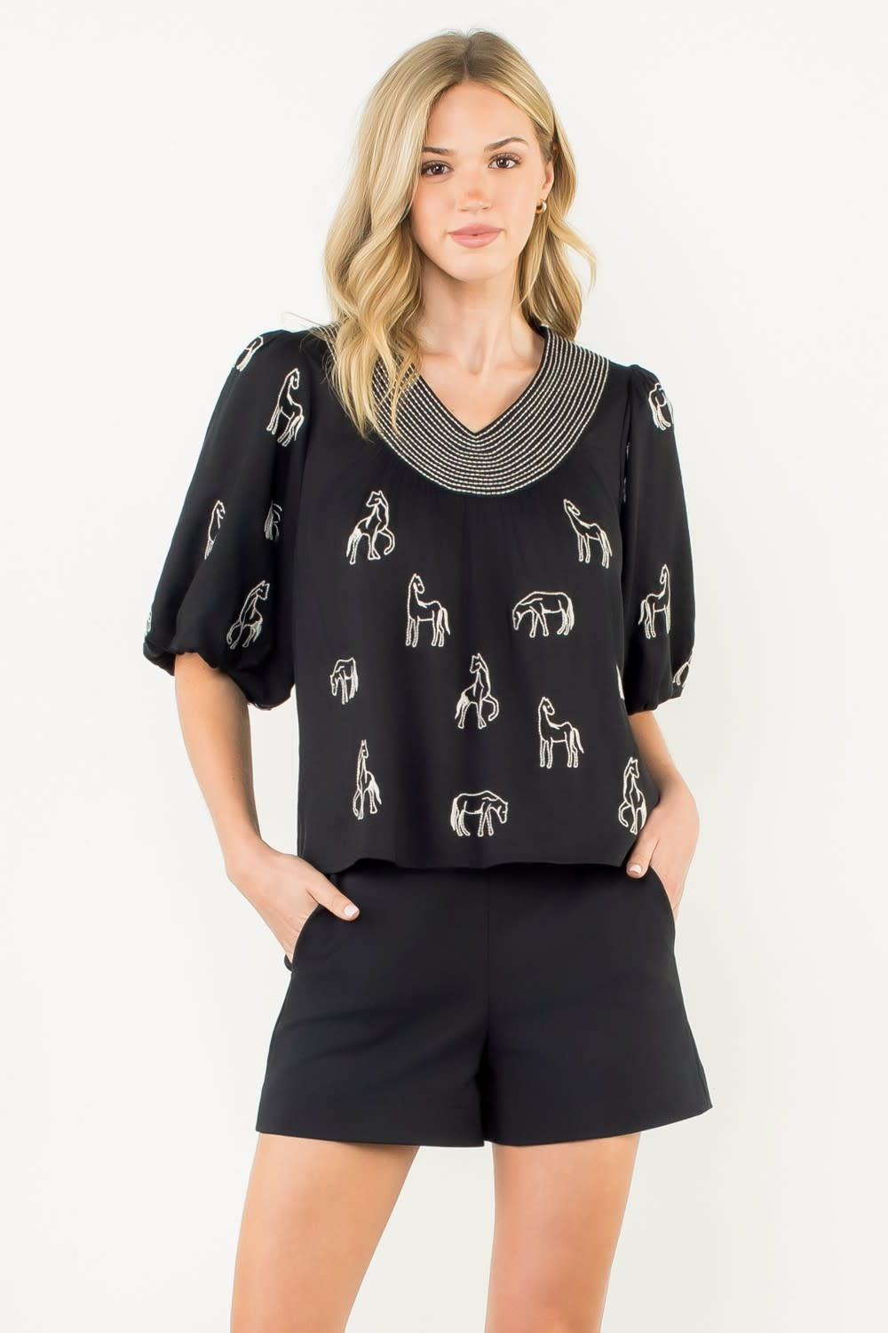 Black woven puff sleeve top with embroidered horse detail on chest.