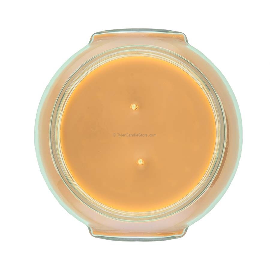 A clear glass jar containing a white candle with the label Tyler Candle.