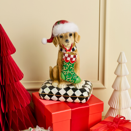 Holiday Lab Dog figurine wearing a Santa hat, holding a stocking, sitting on a checkered pillow.