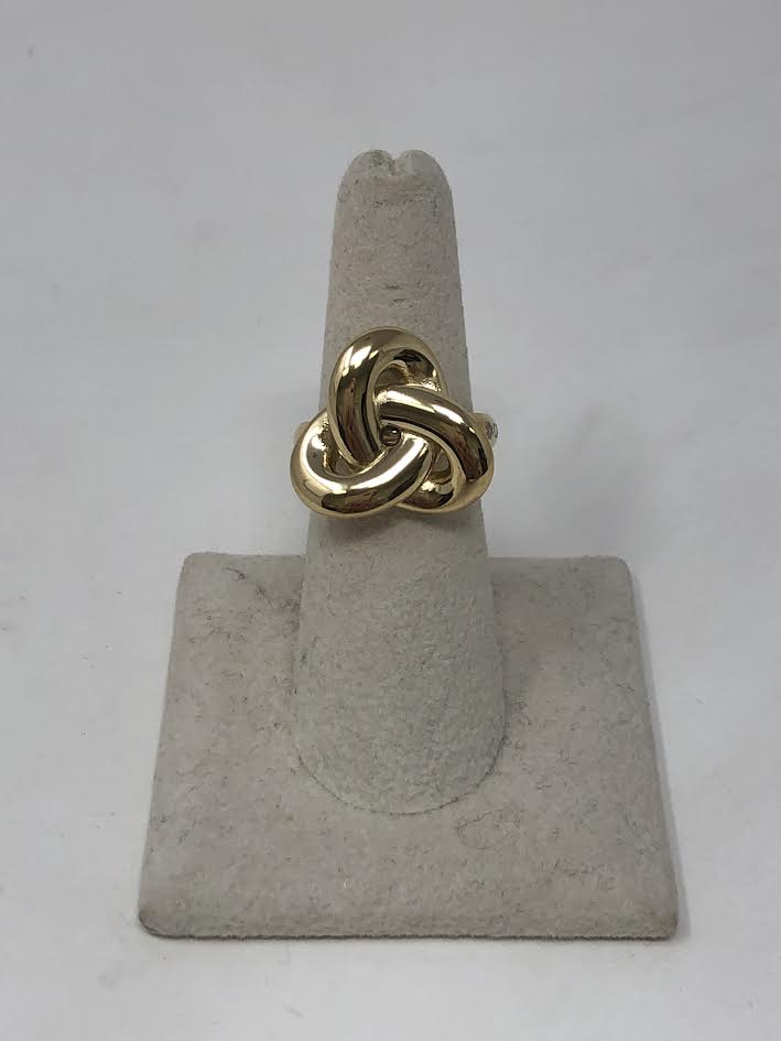 Gold Base Ring NODO featuring a bold 19x20mm polished knot design on a grey display stand.