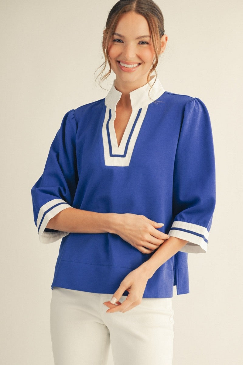 Solid top with three-quarter sleeves, standing neck, color contrast accent trim, side slit hem detail.