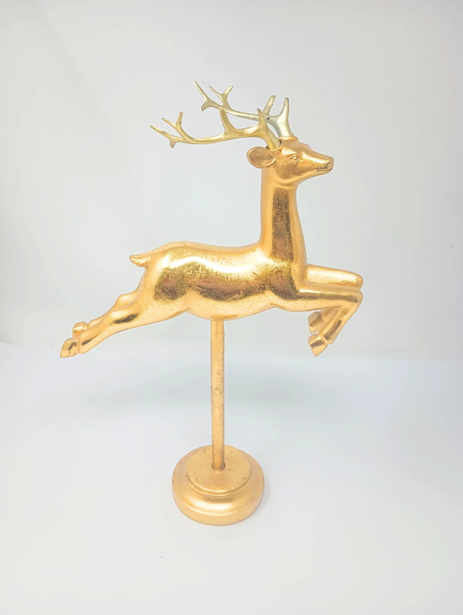 Gold flying reindeer figurine on a matching gold pedestal stand.