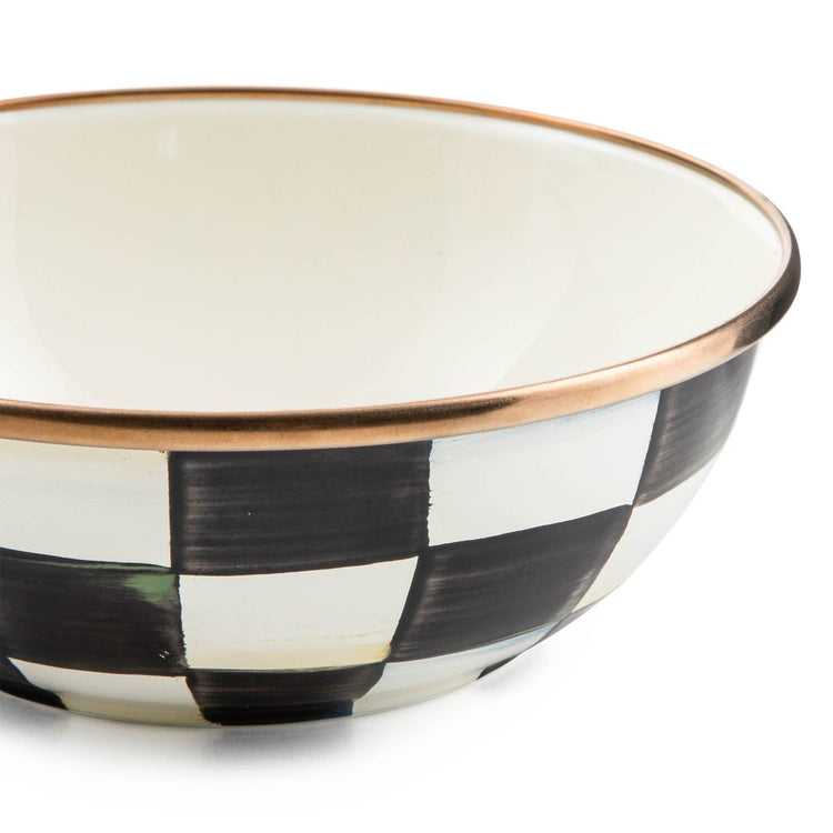 Close-up of a hand-painted black and white checkered enamel bowl with a bronzed stainless steel rim.
