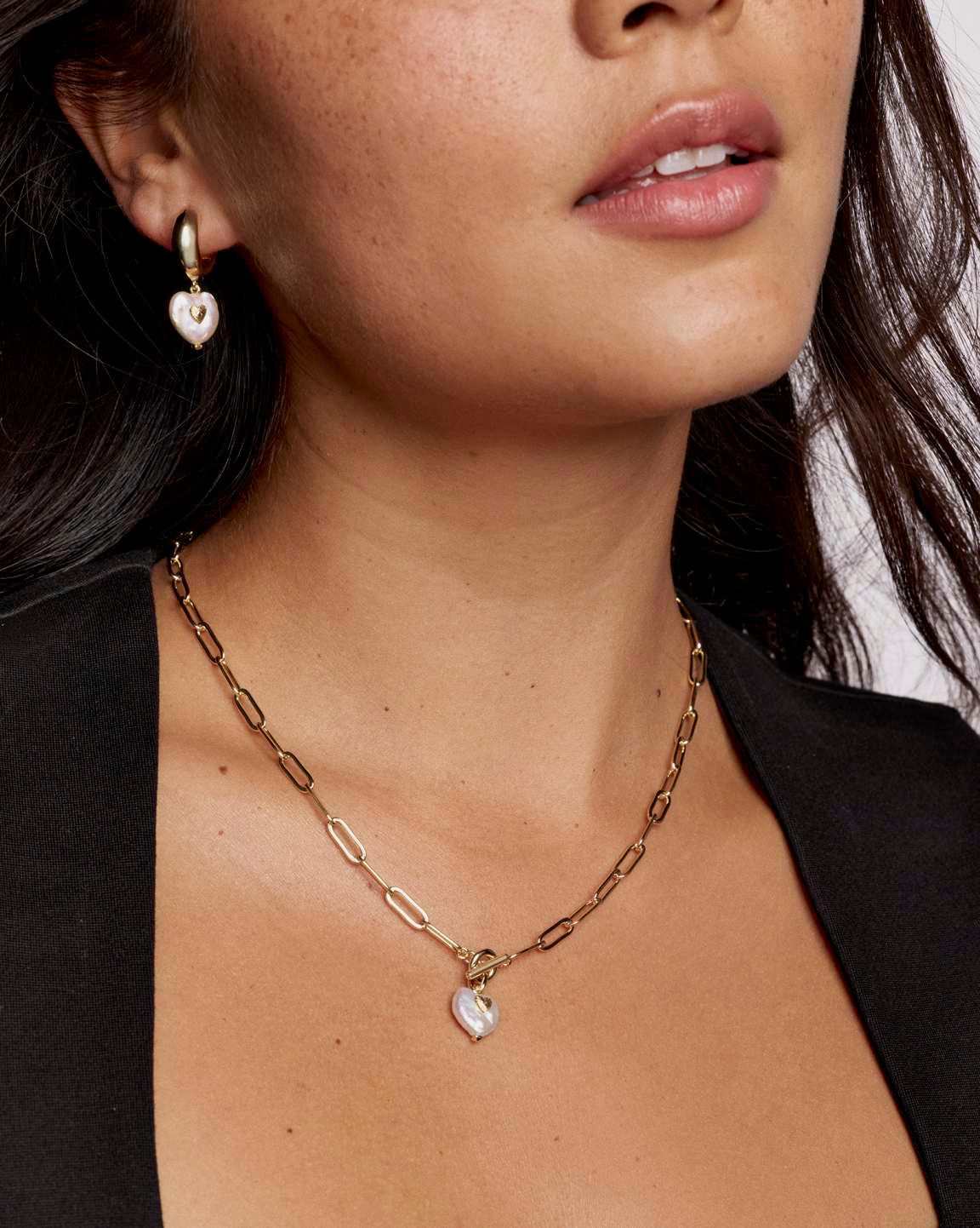 Woman wearing the Sasha Heart Short Pendant Necklace, a gold paperclip chain with a pearl heart.